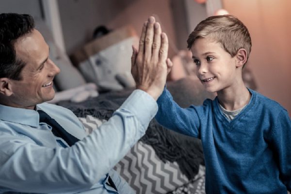 We did it. Handsome man keeping smile on face while spending evening with his son