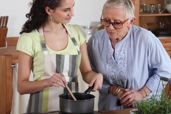 Young woman cooking for an elderly lady