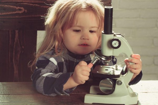boy student studying at his workplace with microscope, educational concept