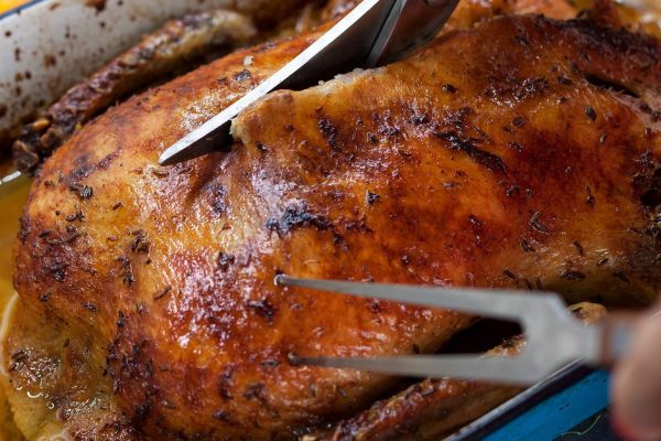 Carving delicious roasted duck with oranges and beer in a pan, rustic style