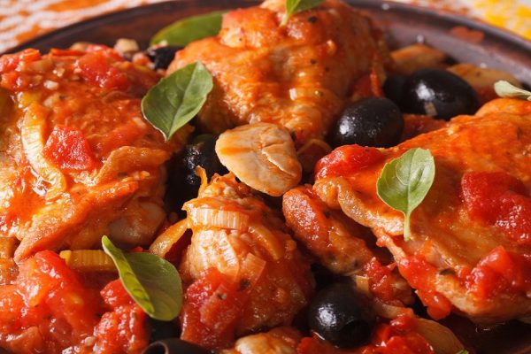 Italian food: Chicken Cacciatori with basil on a plate close-up. horizontal