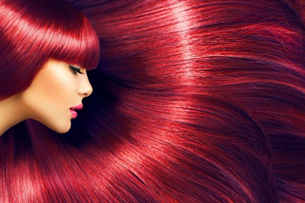 Beautiful hair. Beauty brunette woman with long straight red hair as background