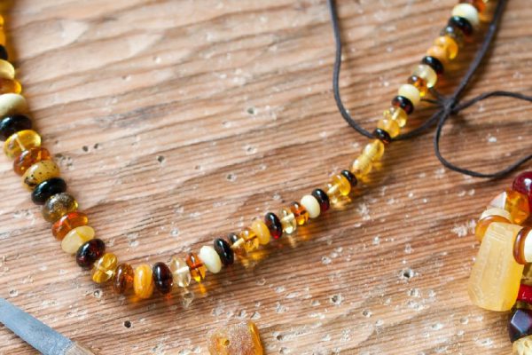 Hand-made ​​necklace using simple tools of ancient amber and colored glass  - in the background tools.