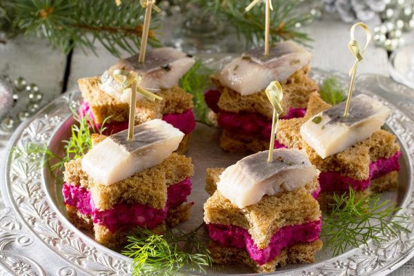 Canapes in the form of a star with pickled herring, beetroot and dill dip. Breakfast table at Christmas or New Year.