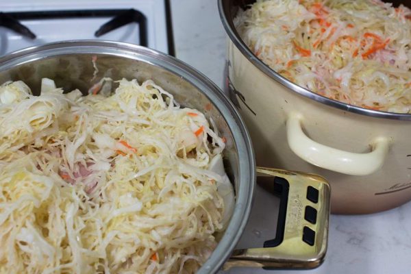 Preparation traditional Polish Bigos based dish of cabbage, sauerkraut, pork shank, beef, sausage juniper, hunting sausage, mushrooms and prunes.