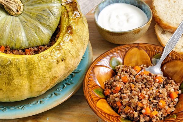 Tasty autumn stuffed pumpkin with buckweat and mushrooms on rustic wooden table