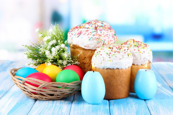 Sweet Easter cakes with colorful eggs on table in room