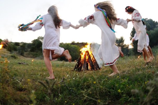Girls in Ukrainian national shirts dancing around a campfire