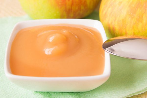 Fresh homemade applesauce (apple puree, babyfood) with green apples and spoon close up, horizontal, vegetarian