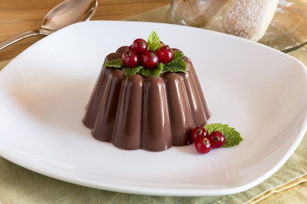 Chocolate pudding with red berries on white dish