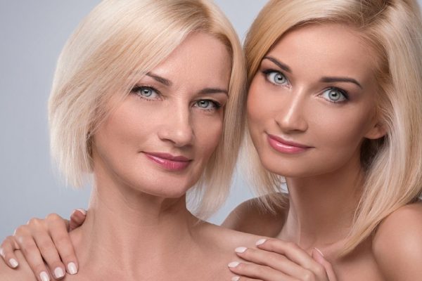 Beautiful middle aged mother and her adult daughter in studio