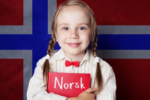 Norwegian concept with smiling kid student with book against the Norway flag background. Learn norwegian language