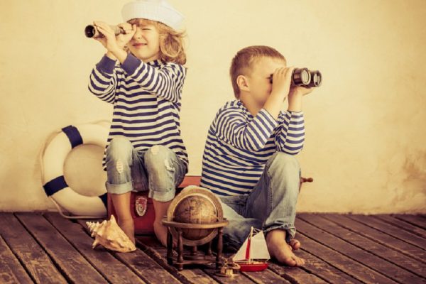 Children playing with vintage nautical things. Kids having fun at home. Travel and adventure concept. Retro toned image