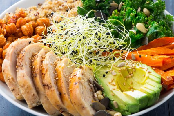 Buddha bowl with kale salad, quinoa, roasted chickpeas, grilled chicken breast, avocado, baked sweet potatoes, leek sprouted seeds, pine nuts, sesame and seeds.