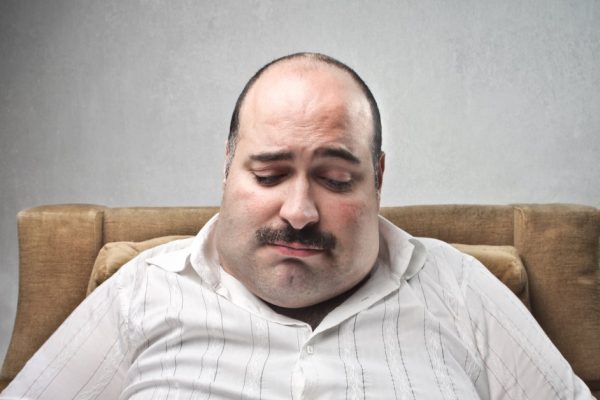 Sad fat man looking at his dish containing barely salad