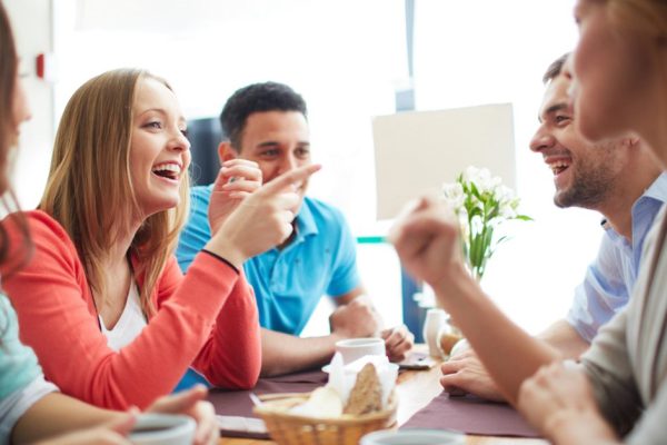 Portrait of happy teenage friends sitting and chatting in cafe