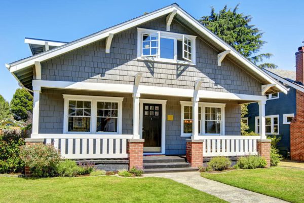 Clapboard siding house exterior. Large entance porch with brick trim and white railings