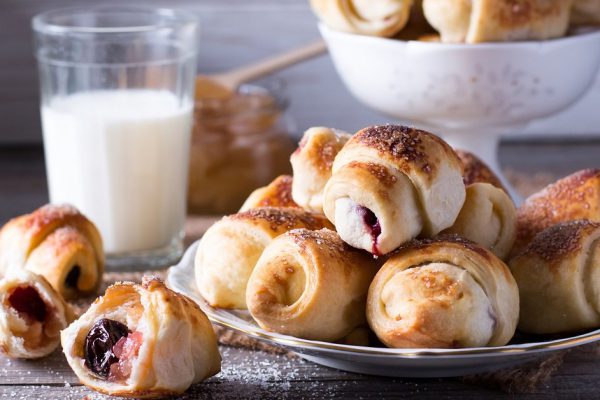 Rugelach with jam filling on plate with milk on background