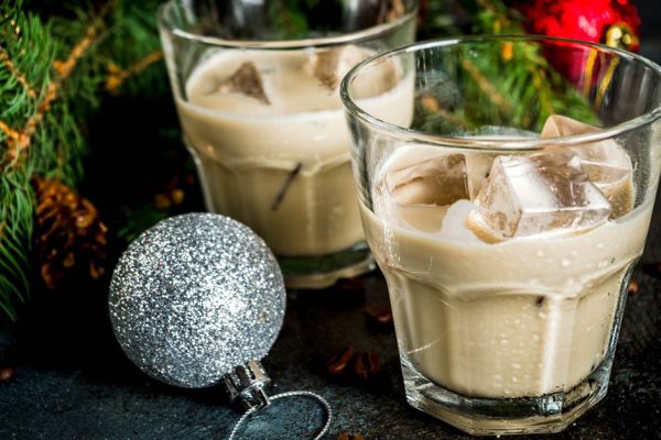 Irish cream cocktail or liqueur, traditional winter christmas drink, dark rusty background with fir tree branches, coffee beans and christmas decorations, copy space