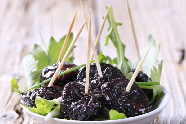 Glazed prunes on a nest of salad greens