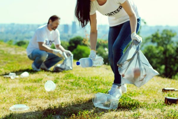 Clean the park. Confident female raising eyebrows and pressing lips while looking for garbage