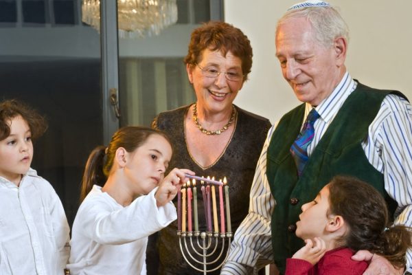 Grandperents and grandchildren lightening Hanukkiyah together