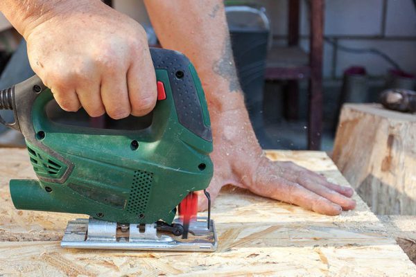 Construction worker use jig saw for cutting a Wood Particle Board or fiberboard