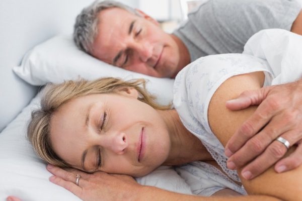 Couple sleeping and spooning in bed in bedroom at home