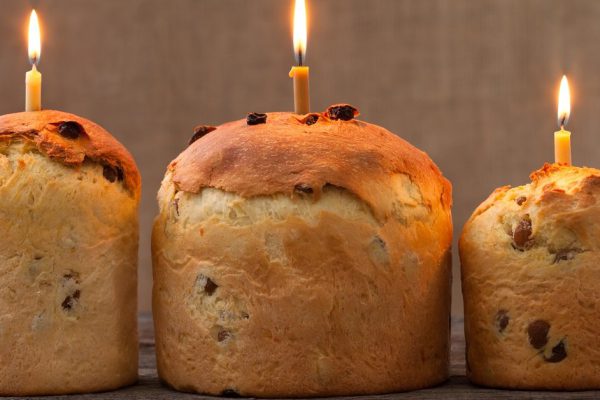 Baked traditional religious easter holiday sweet cake also called kulich with raisins and burning candle on vintage textile background