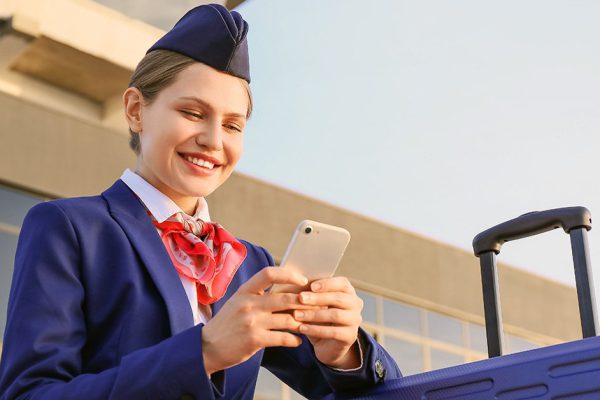 Young stewardess with mobile phone outdoors