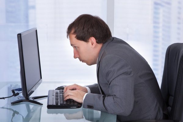 Side view of concentrated businessman working on computer at desk in office