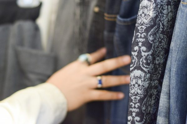 Hand browsing racks of shirts and pants at a stylish boutique