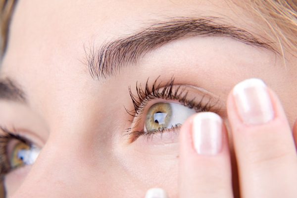 Opened green eyes and fingernails with french manicure close-up