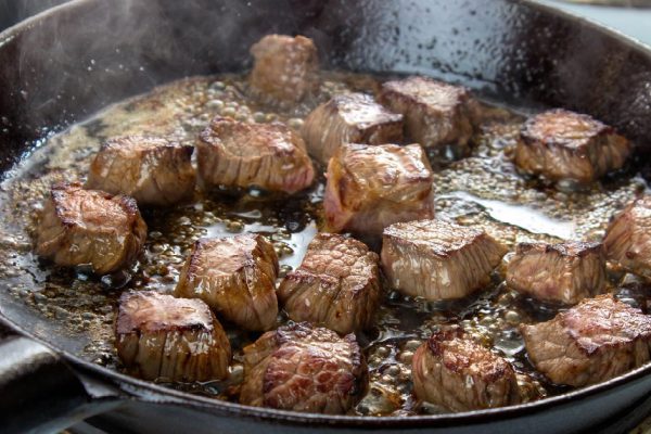 *** Local Caption *** Frying beef bottom round roast cubes in cast iron skillet , meat flipped once