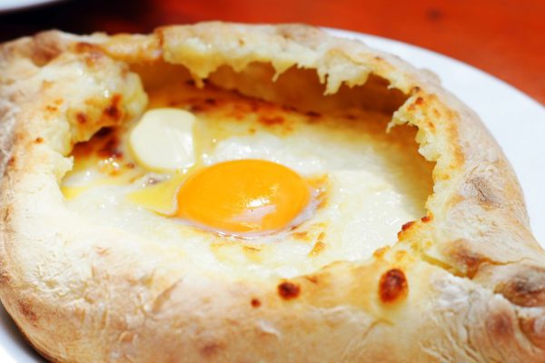 Ajarian or Adjaruli khachapuri, filled with cheese and topped with a raw egg and butter - traditional dish of georgian cuisine