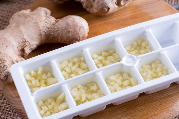 Frozen ginger cubes on a cutting board on a wooden table