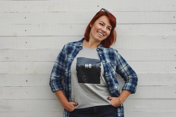 happy redhead woman standing near the wall