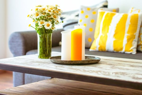 Modern wooden coffee table and cozy sofa with pillows. Living room interior and home decor concept