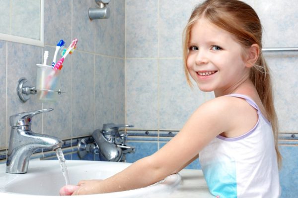 Little girl washing with soap in bathroom