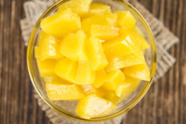 Canned Peaches (close-up shot) on vintage wooden background