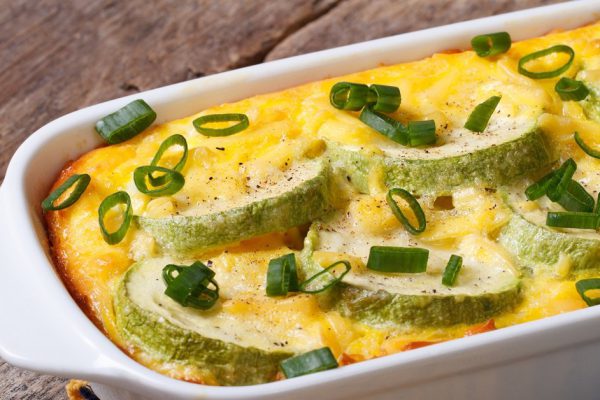 Zucchini baked with cheese, eggs and onion closeup in a white dish. horizontal