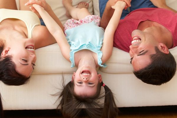 Family Lying Upside Down On Sofa With Daughter