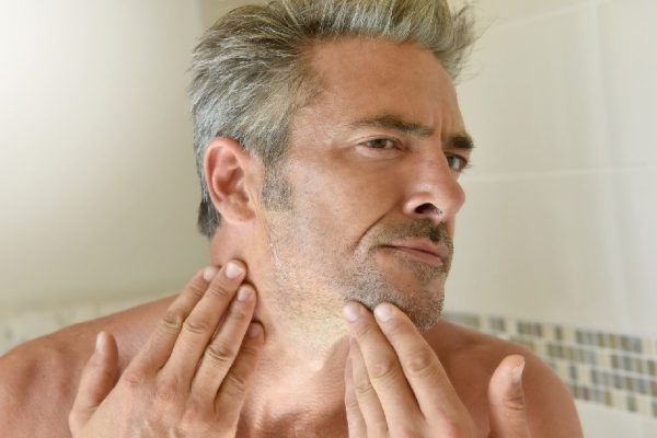 Mature man in bathroom checking beard