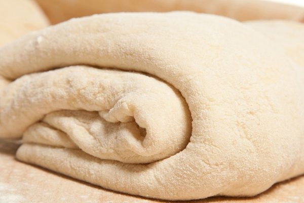 Kneading dough: close-up of dough portion; white background