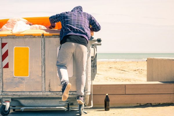 Young tramp rummaging in trash container looking for food and reusable goods - Modern concept of poverty with normal citizens becoming suddenly poor - Economy crisis and people with living issues