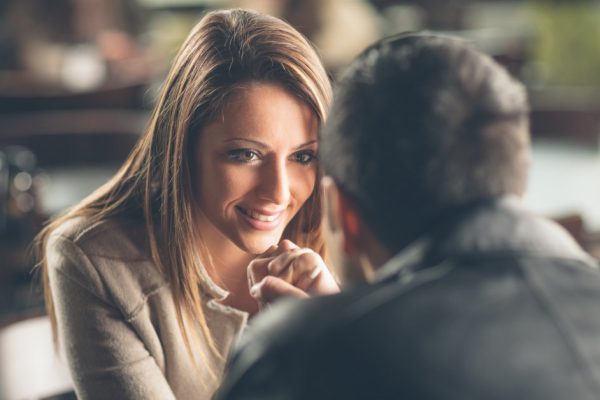 Romantic young couple dating and flirting at the bar, staring at each other's eyes