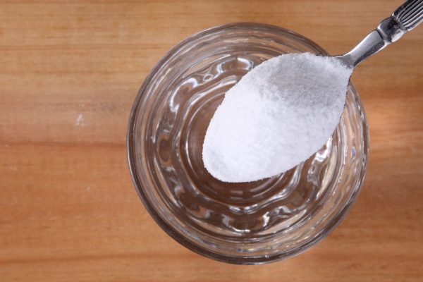 pouring baking soda to glass of water on the wooden background