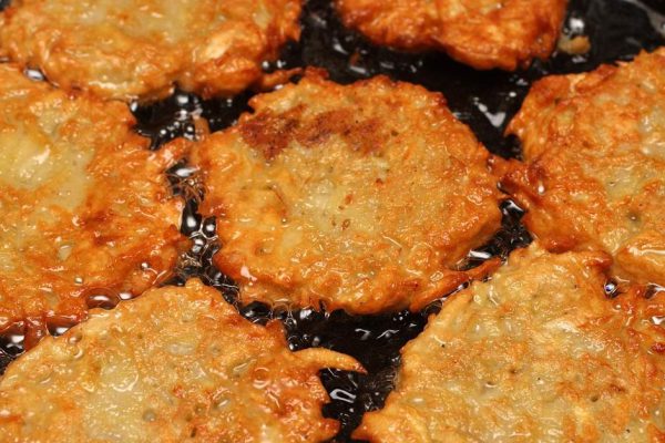 potato pancakes frizzle in black frying pan