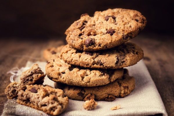 Chocolate cookies on white linen napkin on wooden table. Chocolate chip cookies shot on coffee colored cloth, closeup.