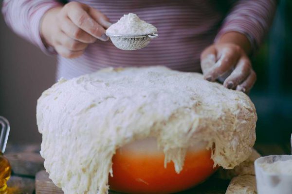 Close up view of baker kneading dough. Homemade bread. Hands preparing bread dough on wooden table. Preparing traditional homemade bread. Woman hands kneading fresh dough for making bread